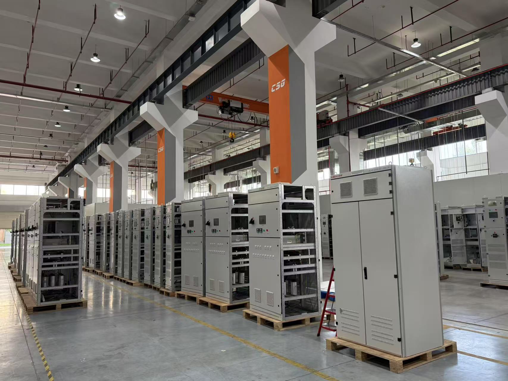 Rows of industrial electrical switchgear and control cabinets on a manufacturing plant floor